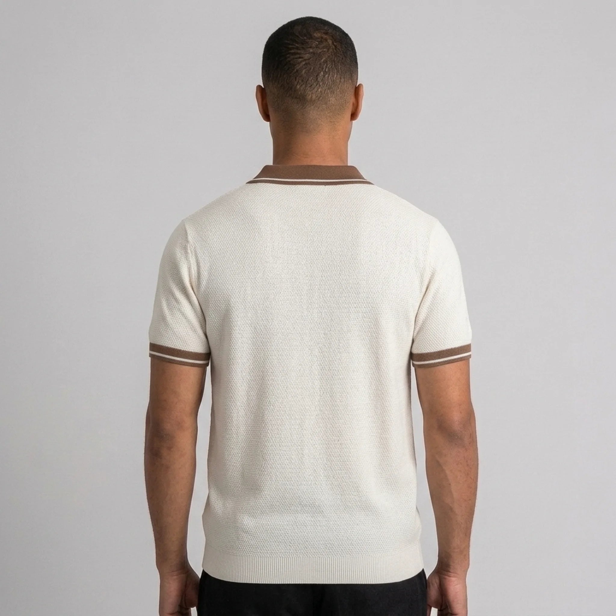 Back view of man wearing apricot color block knit polo shirt with lapel collar