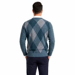 Man wearing MannerCo green V-neck argyle knitted sweater slim fit, side view lifestyle indoor