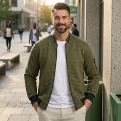 Man wearing MannerCo army green quilted zip-up baseball jacket in outdoor lifestyle setting