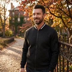 Man wearing MannerCo black quilted zip-up baseball jacket in outdoor lifestyle setting