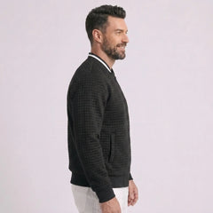 Man wearing MannerCo black quilted zip-up baseball jacket with stand collar, side view