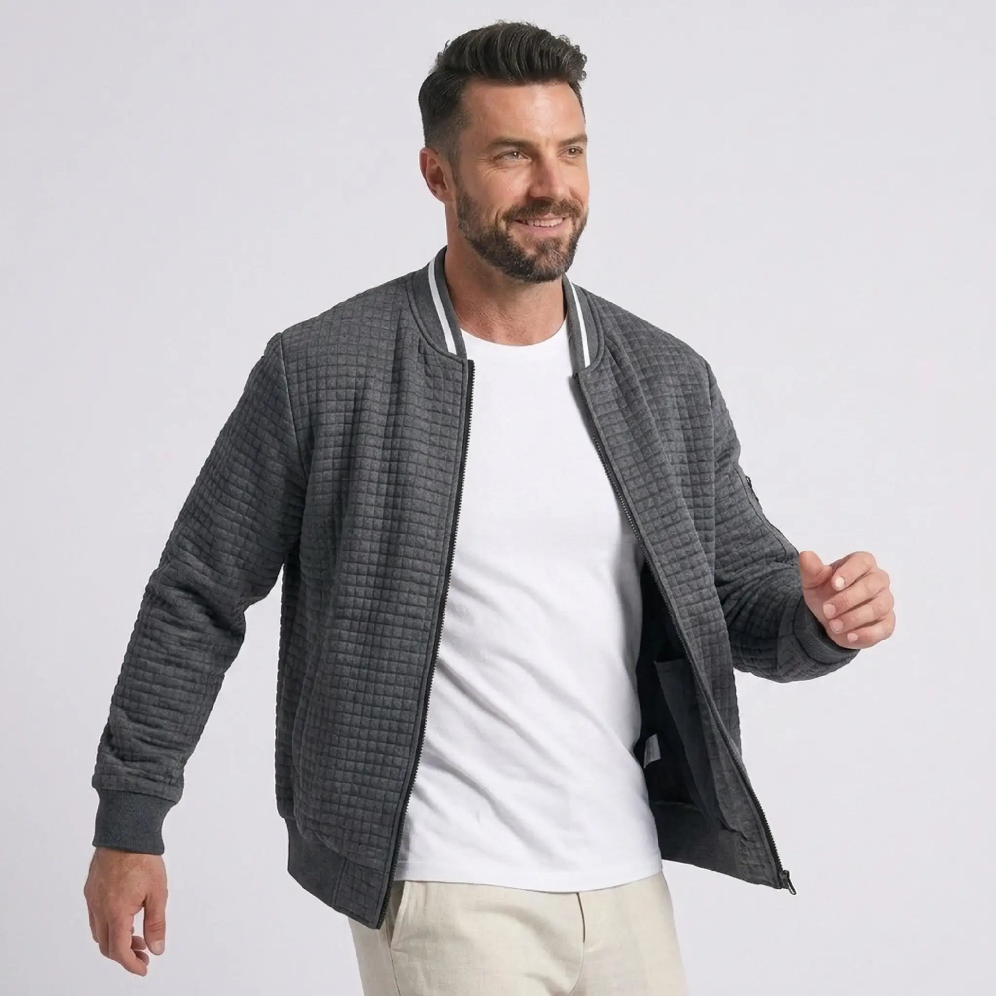 Man wearing MannerCo dark gray quilted zip-up baseball jacket with stand collar, front view