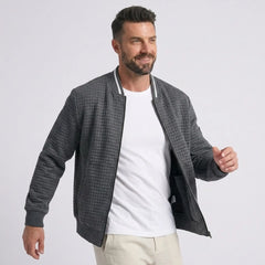 Man wearing MannerCo dark gray quilted zip-up baseball jacket with stand collar, front view