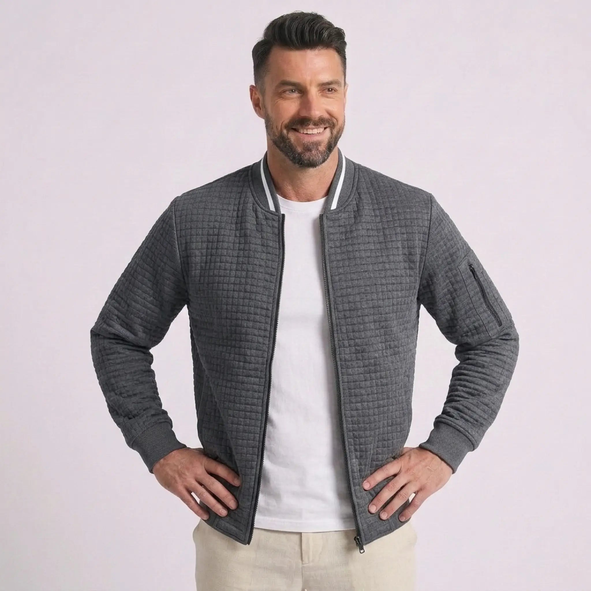 Man wearing MannerCo dark gray quilted zip-up baseball jacket with stand collar, front view