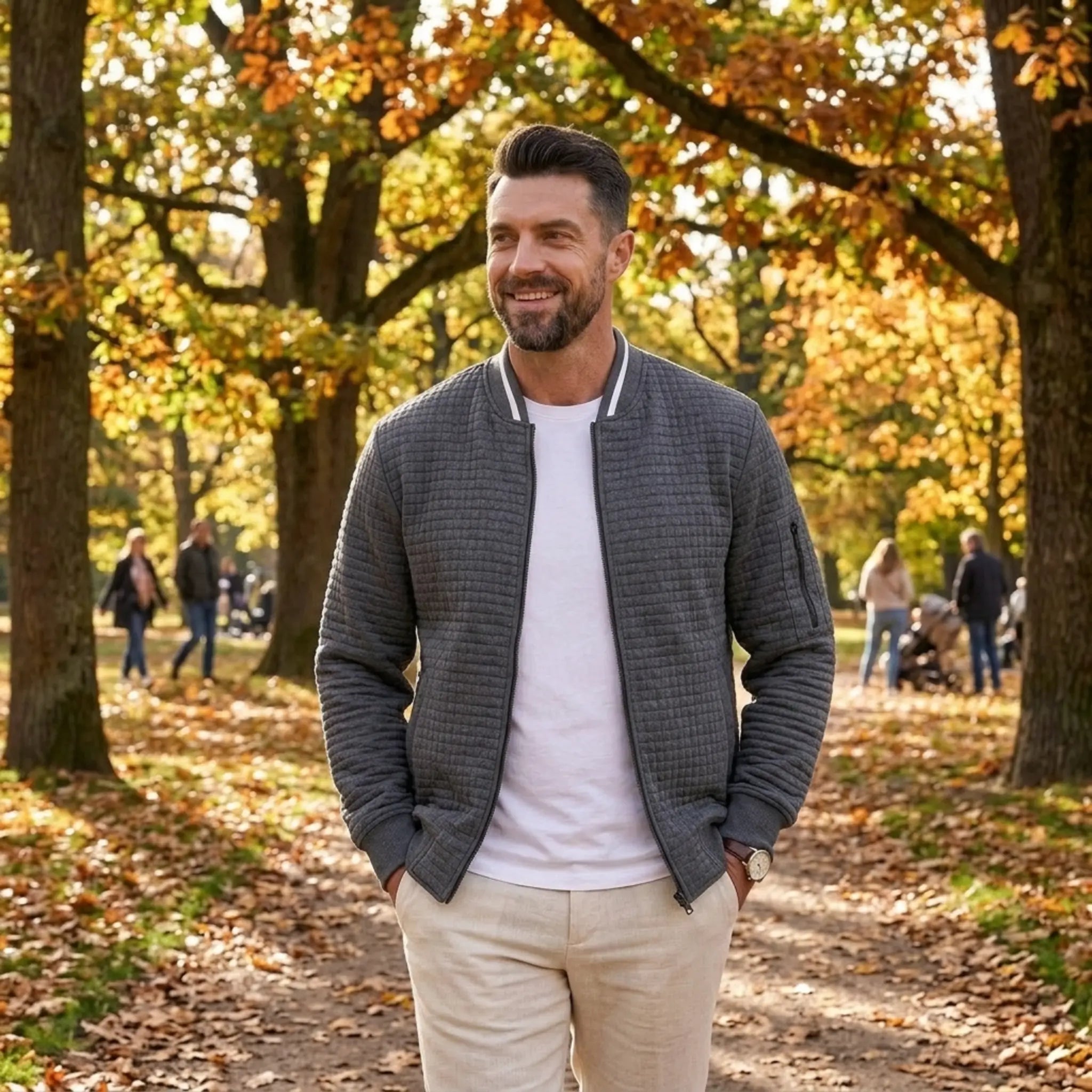 Man wearing MannerCo dark gray quilted zip-up baseball jacket in outdoor lifestyle setting