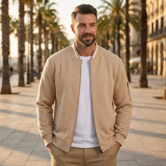 Man wearing MannerCo khaki quilted zip-up baseball jacket in outdoor lifestyle setting