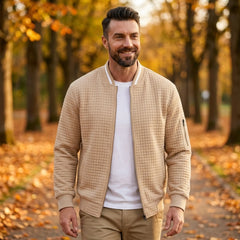 Man wearing MannerCo khaki quilted zip-up baseball jacket in outdoor lifestyle setting