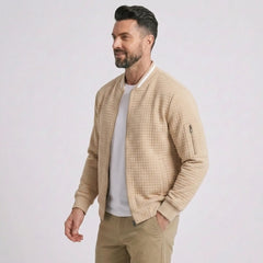 Man wearing MannerCo khaki quilted zip-up baseball jacket with stand collar, side view