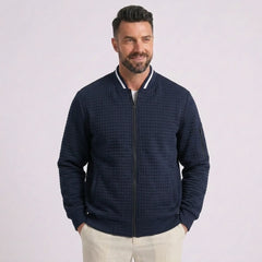 Man wearing MannerCo navy quilted zip-up baseball jacket with stand collar, front view