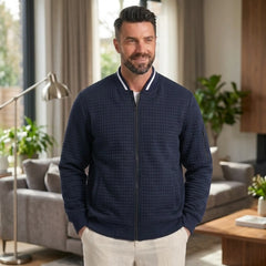 Man wearing MannerCo navy quilted zip-up baseball jacket in outdoor lifestyle setting