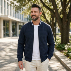 Man wearing MannerCo navy quilted zip-up baseball jacket in outdoor lifestyle setting