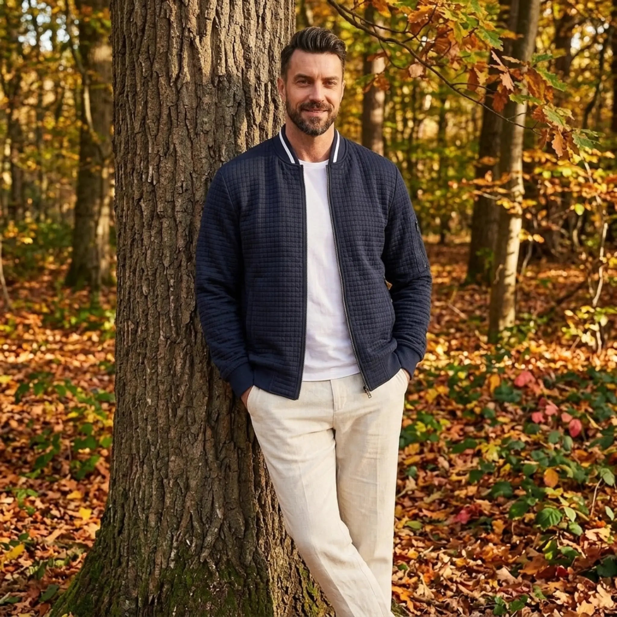 Man wearing MannerCo navy quilted zip-up baseball jacket in outdoor lifestyle setting