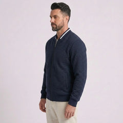 Man wearing MannerCo navy quilted zip-up baseball jacket with stand collar, side view