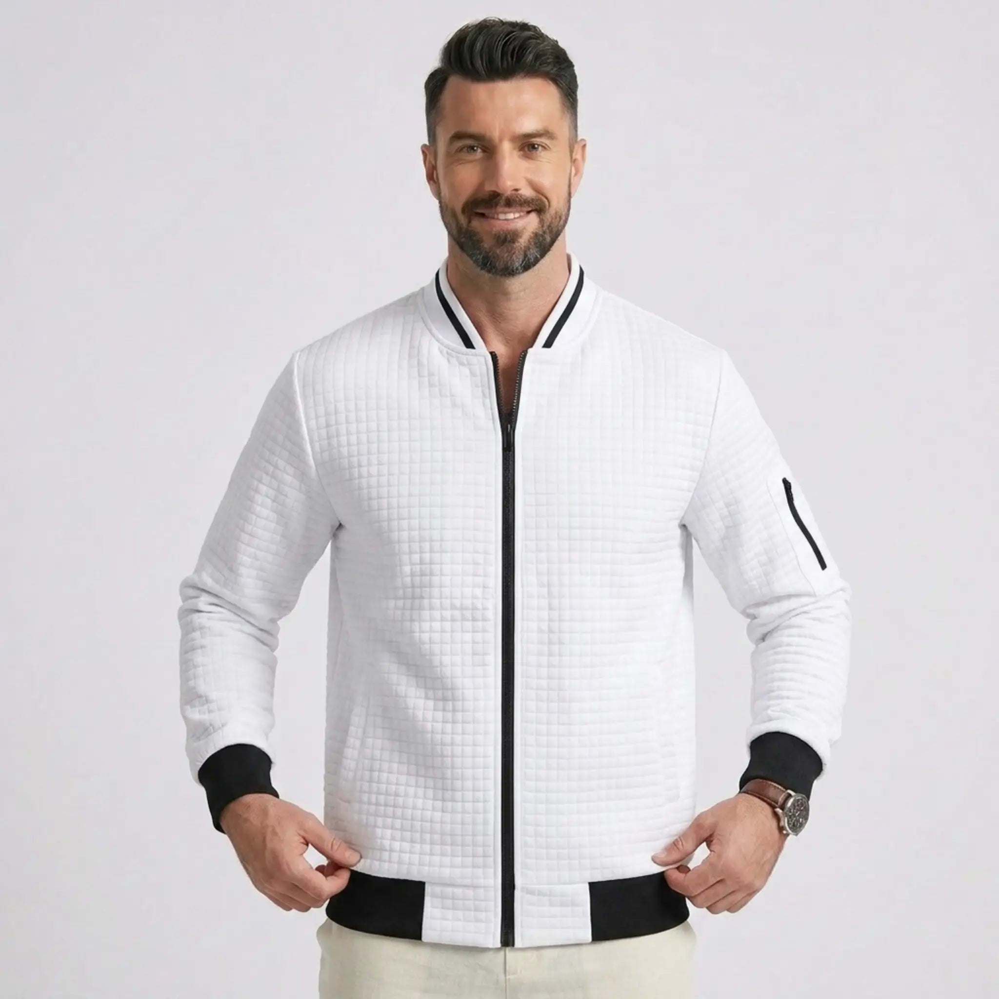 Man wearing MannerCo white quilted zip-up baseball jacket with black ribbed collar and cuffs, front view
