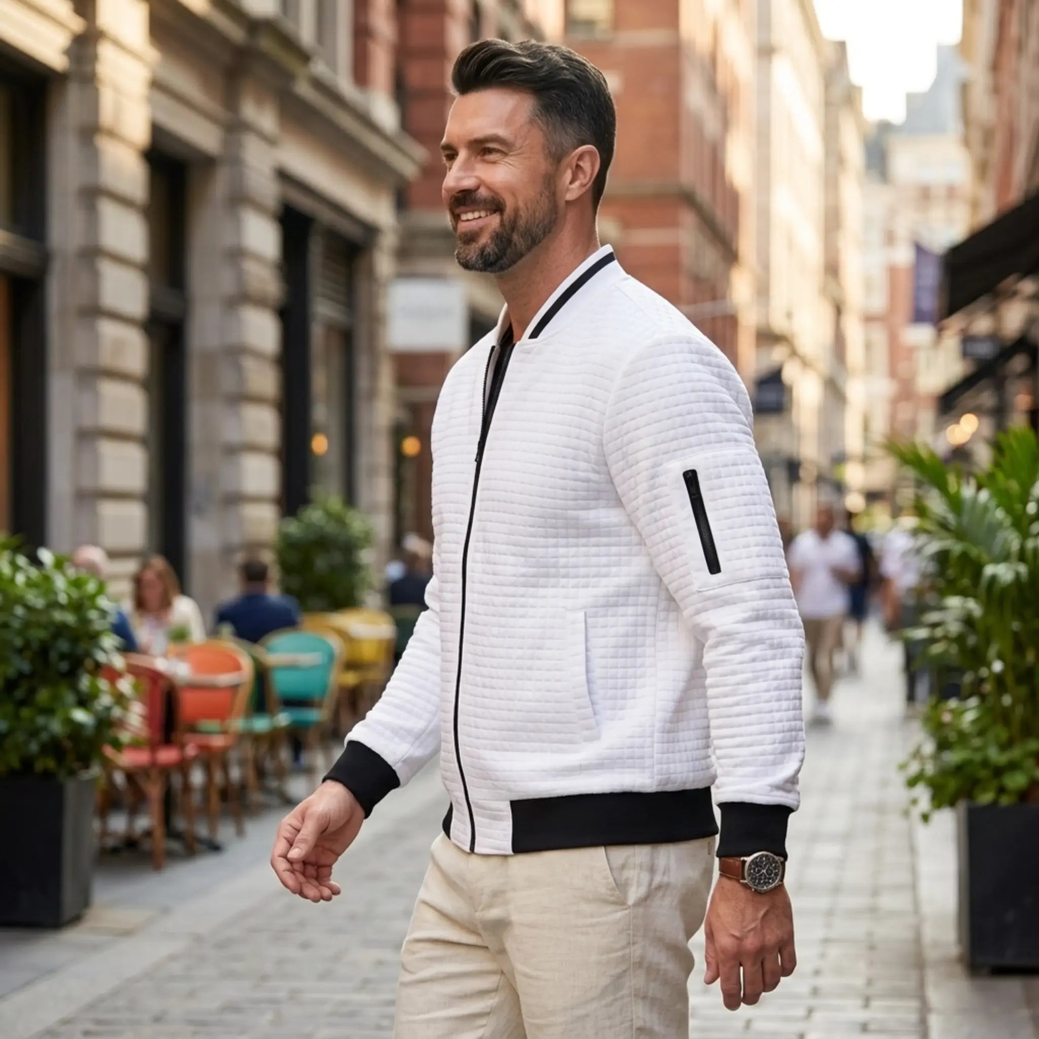 Man wearing MannerCo white quilted zip-up baseball jacket in outdoor lifestyle setting