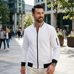Man wearing MannerCo white quilted zip-up baseball jacket in outdoor lifestyle setting