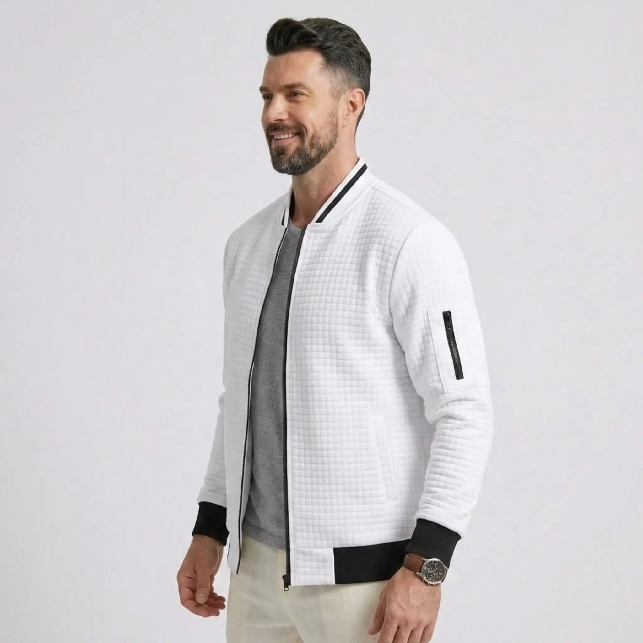 Man wearing MannerCo white quilted zip-up baseball jacket with black ribbed collar, side view