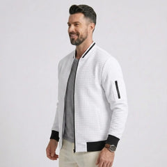 Man wearing MannerCo white quilted zip-up baseball jacket with black ribbed collar, side view