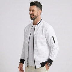 Man wearing MannerCo white quilted zip-up baseball jacket with black ribbed collar, side view