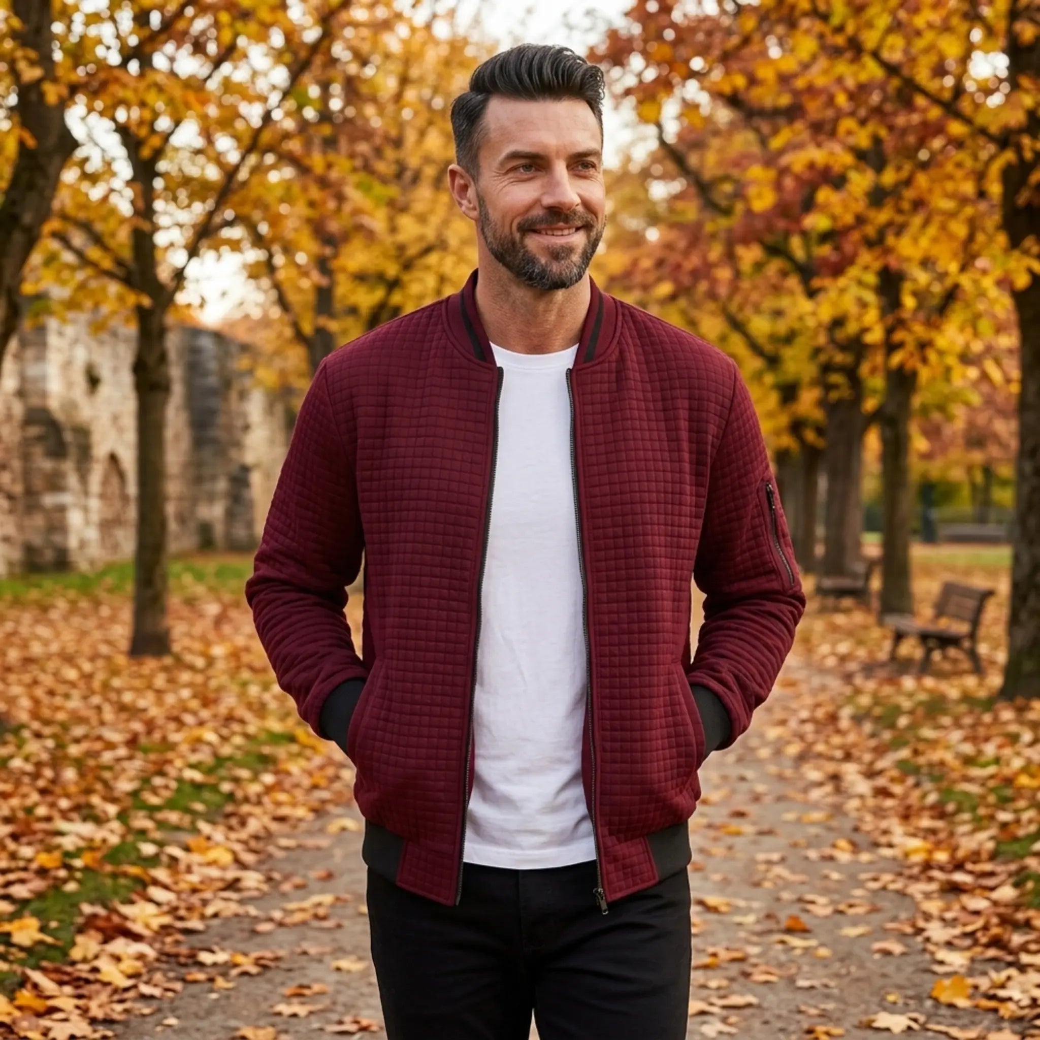Man wearing MannerCo wine red quilted zip-up baseball jacket in outdoor lifestyle setting