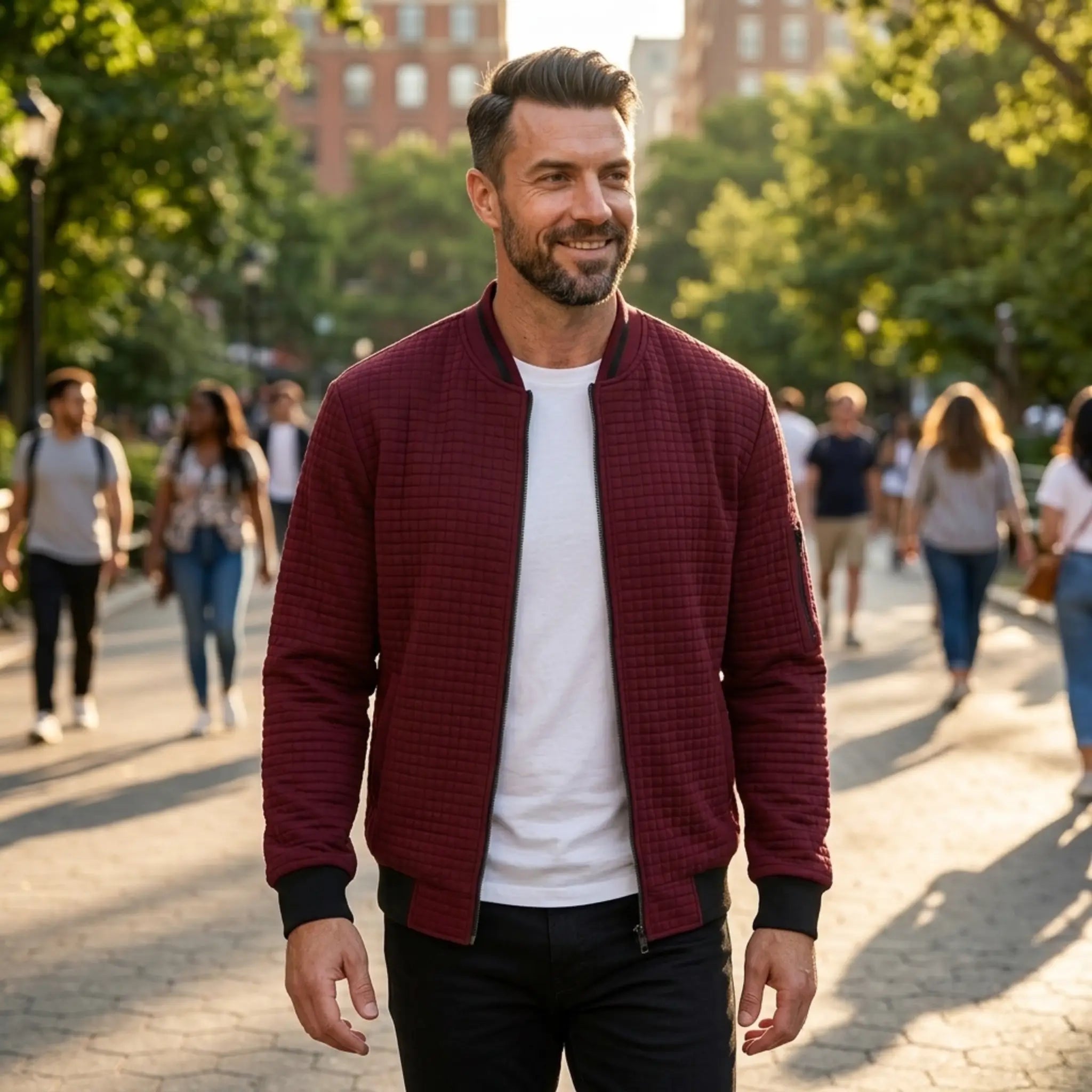 Man wearing MannerCo wine red quilted zip-up baseball jacket in outdoor lifestyle setting