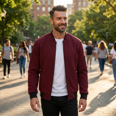Man wearing MannerCo wine red quilted zip-up baseball jacket in outdoor lifestyle setting