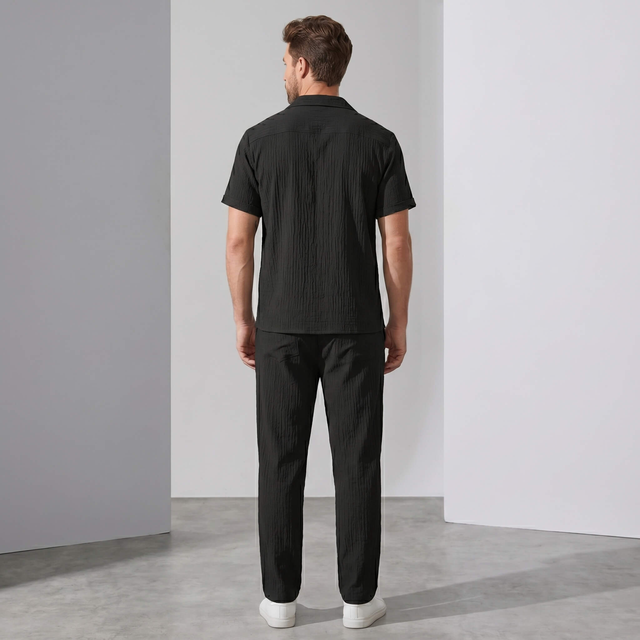Back view of man wearing beige crinkled textured button up shirt and straight leg pants