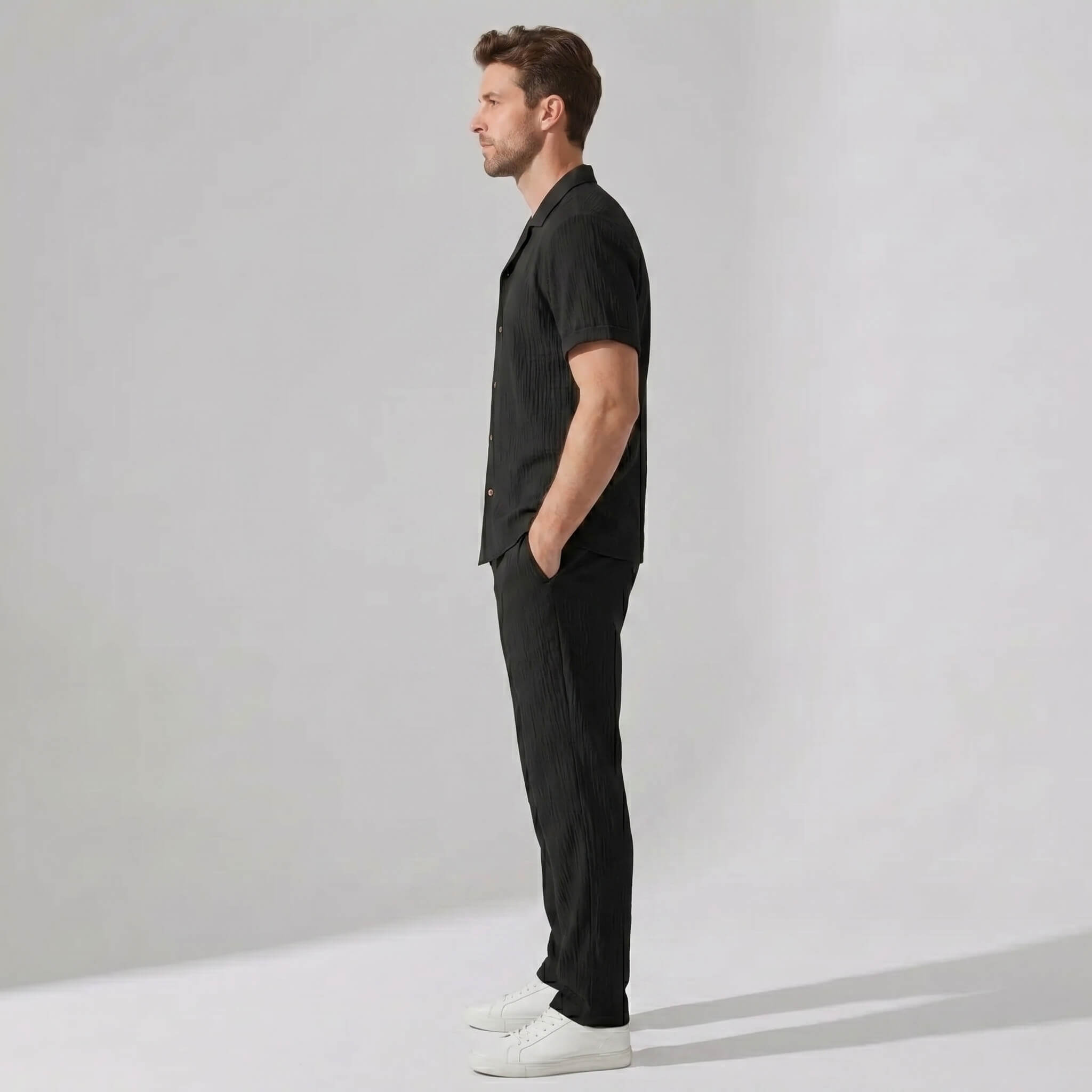 Side view of man in beige crinkled textured button up shirt and straight leg pants
