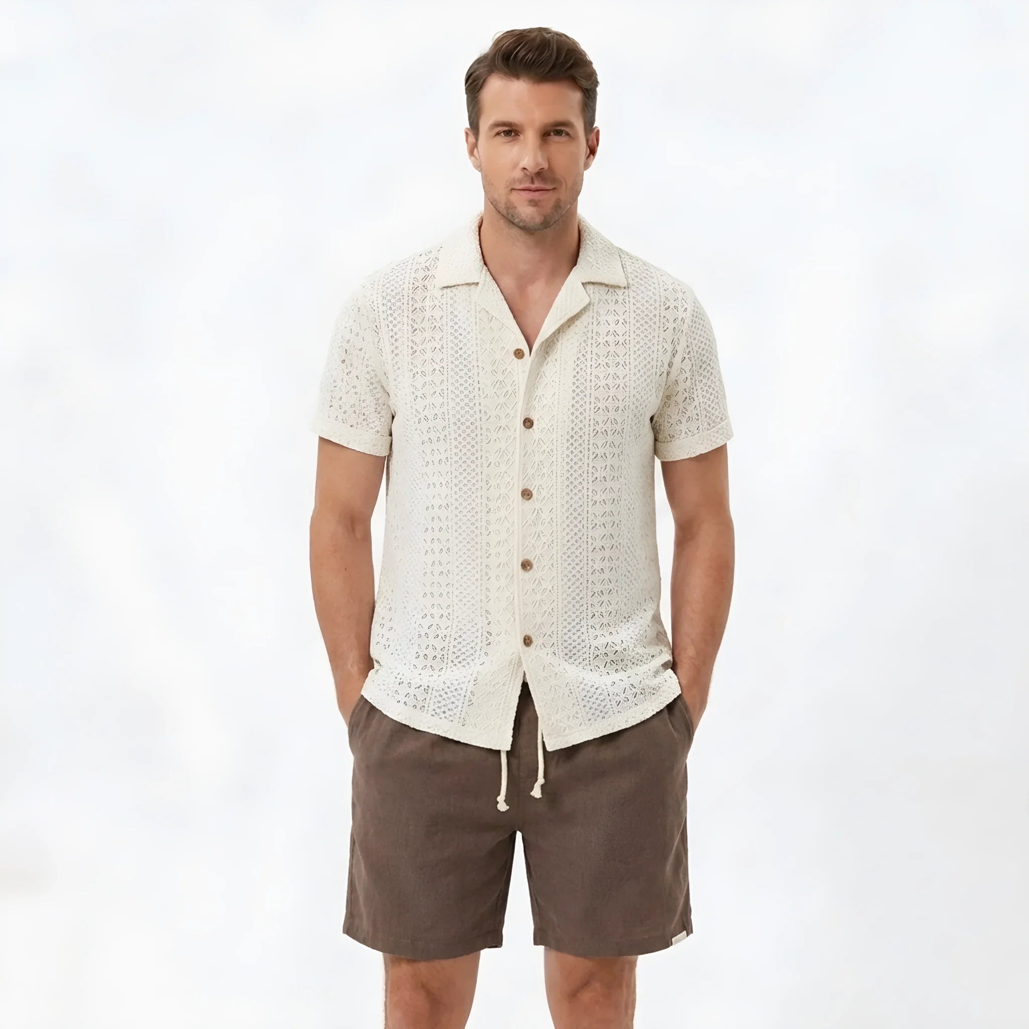 Back view of man wearing beige floral checkerboard jacquard Cuban shirt and linen drawstring shorts