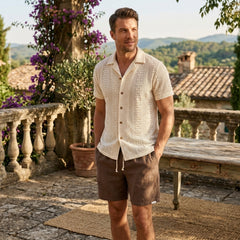 Man wearing beige floral checkerboard jacquard Cuban shirt and linen drawstring shorts in outdoor lifestyle