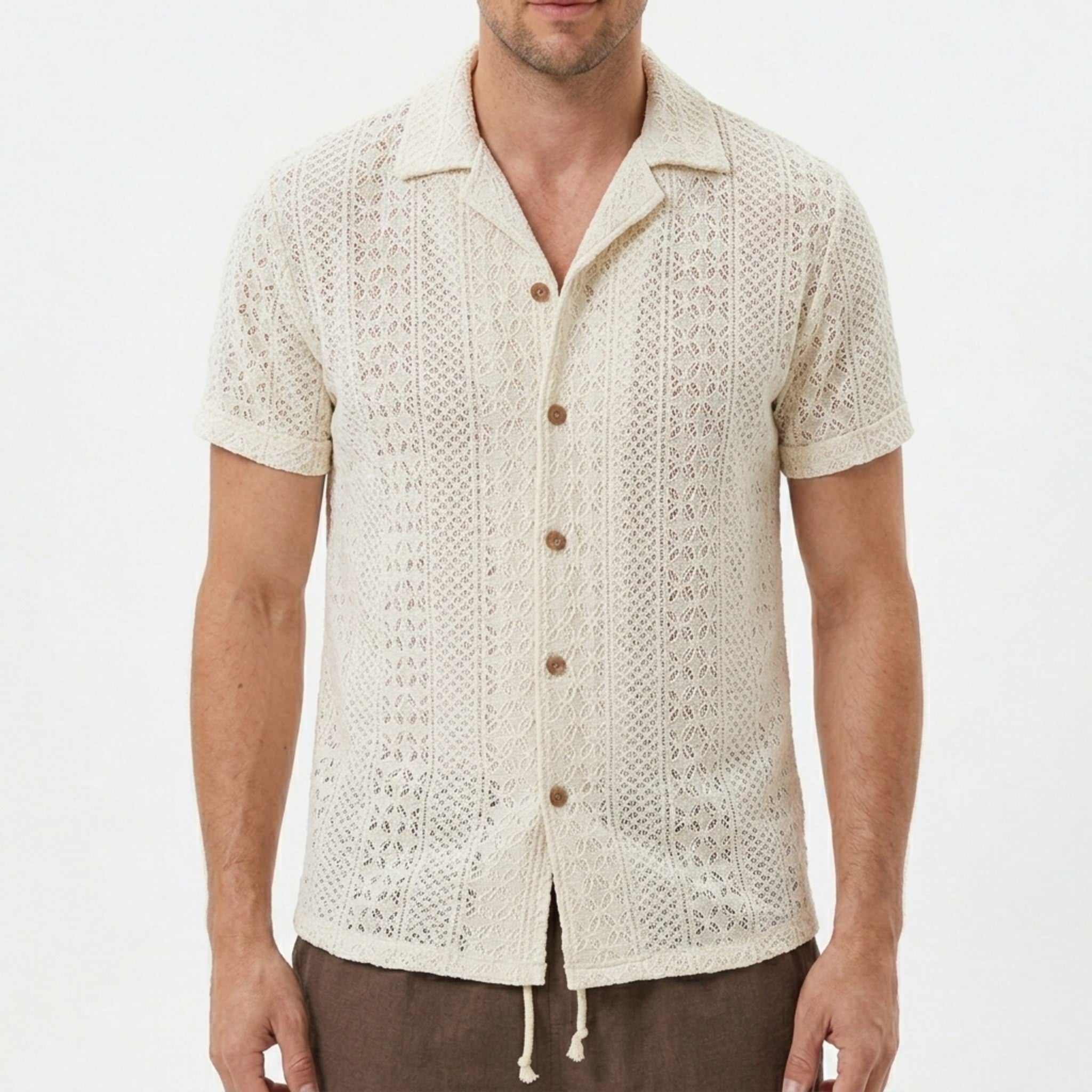 Three quarter view of man in beige floral checkerboard jacquard Cuban shirt and drawstring shorts