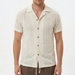Three quarter view of man in beige floral checkerboard jacquard Cuban shirt and drawstring shorts
