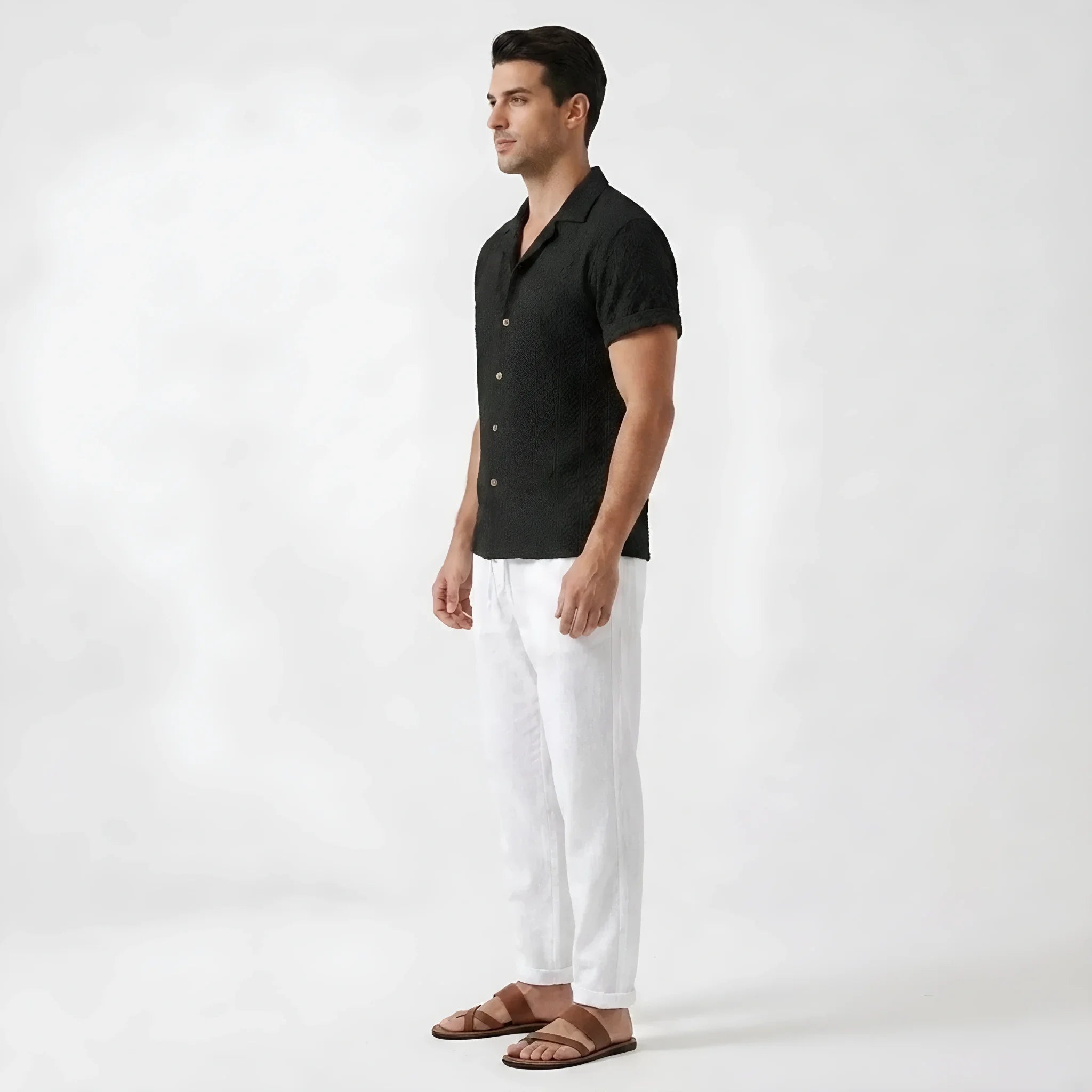 Man wearing beige floral checkerboard jacquard Cuban shirt and linen pants in sunny outdoor environment