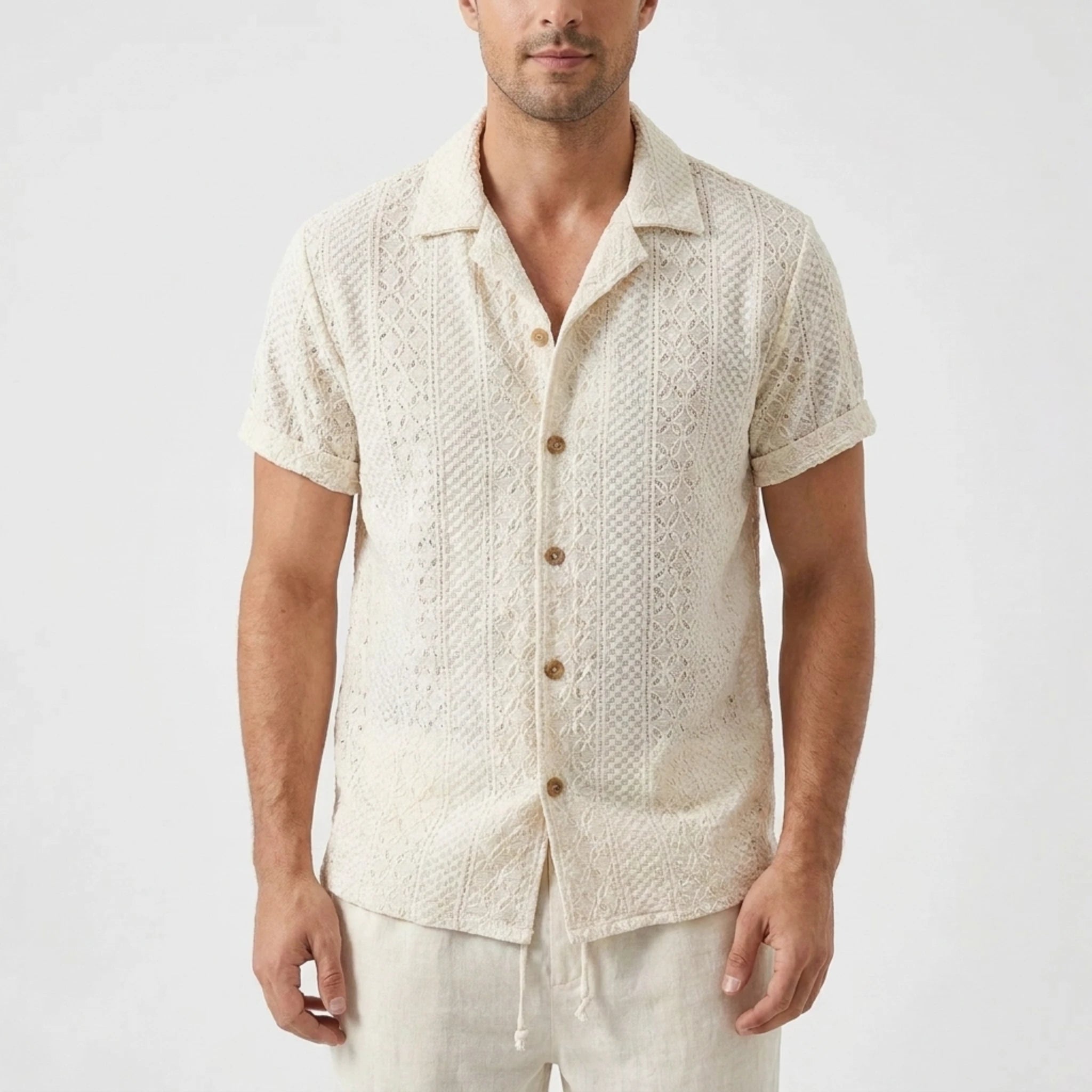 Three quarter view of man in beige floral checkerboard jacquard Cuban shirt and linen pants