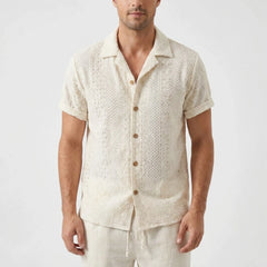 Three quarter view of man in beige floral checkerboard jacquard Cuban shirt and linen pants