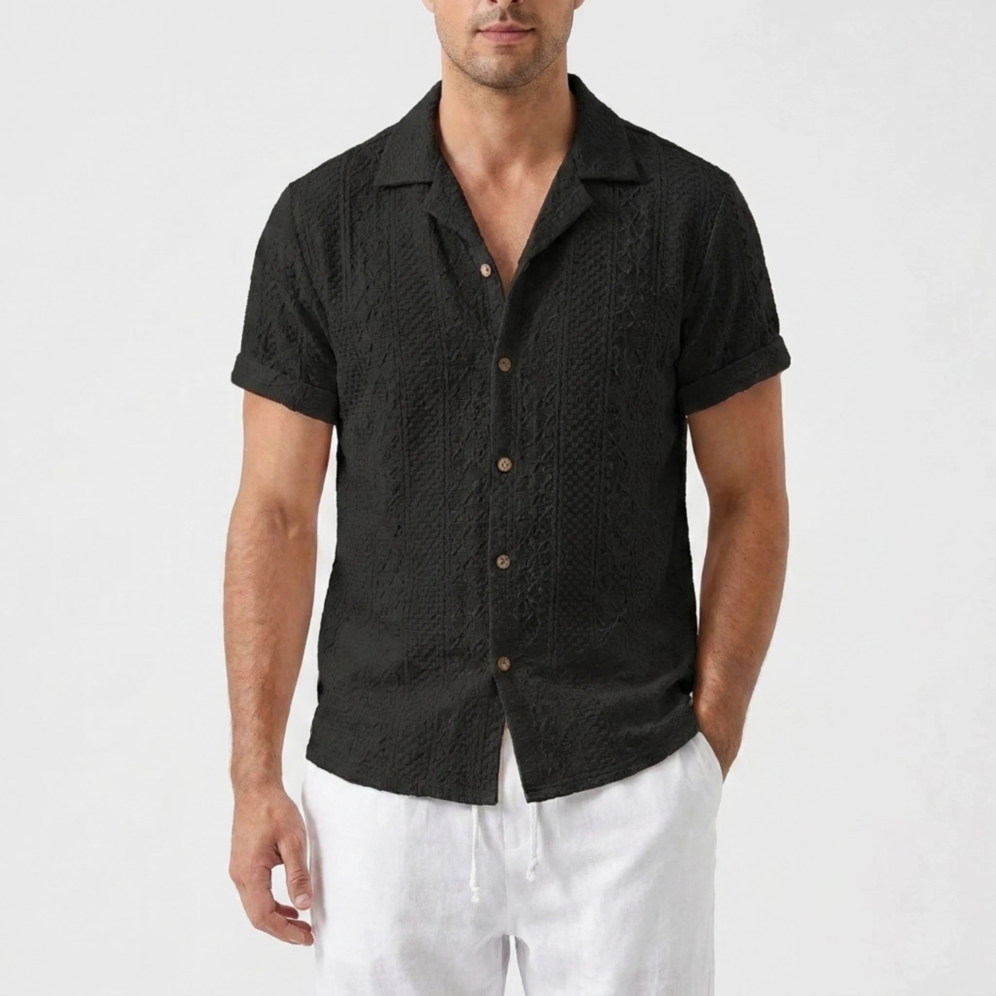 Man in beige floral checkerboard jacquard Cuban shirt and linen pants in warm outdoor scene