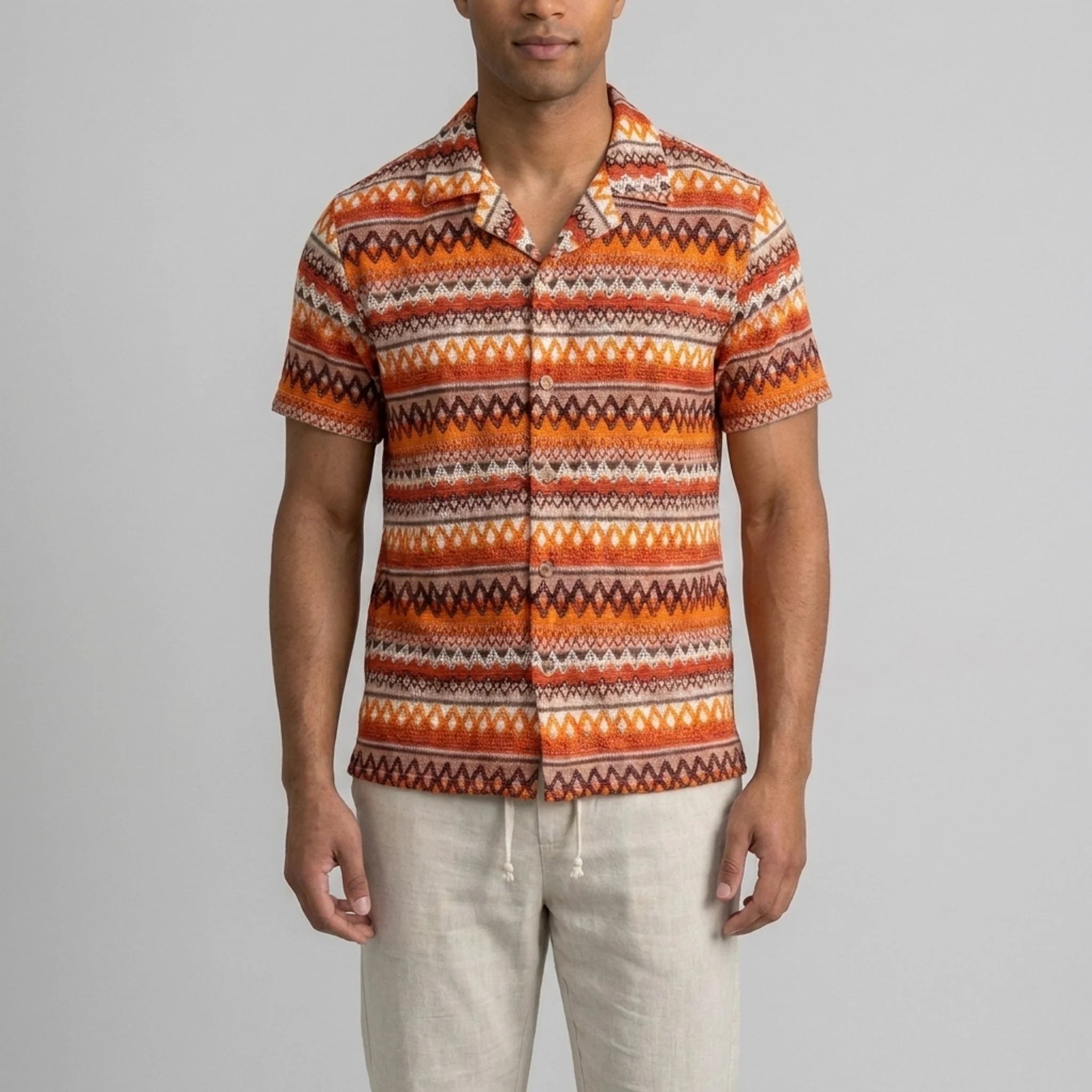 Back view of man wearing beige geometric Cuban shirt and straight leg linen pants