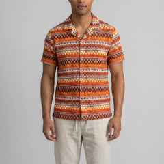 Back view of man wearing beige geometric Cuban shirt and straight leg linen pants