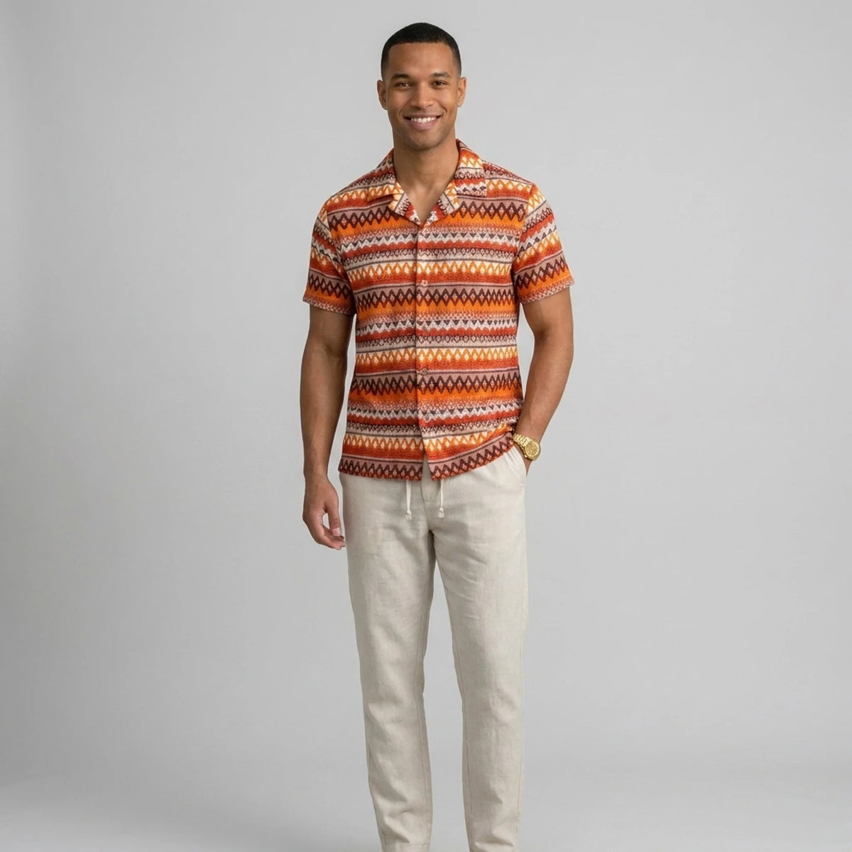 Man wearing a beige geometric Cuban shirt and straight leg linen pants front view on plain background