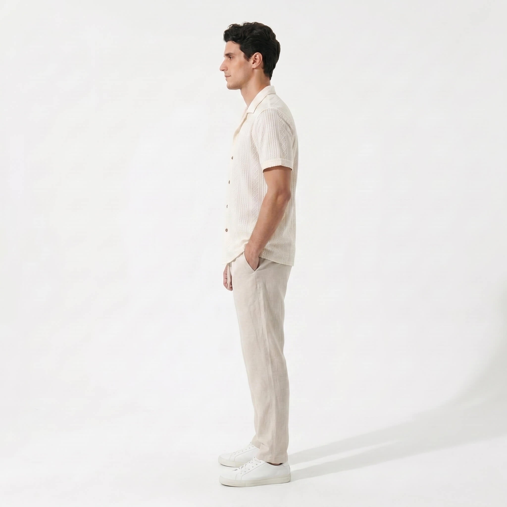 Side view of Man wearing beige geometric jacquard button up shirt and beige linen pants