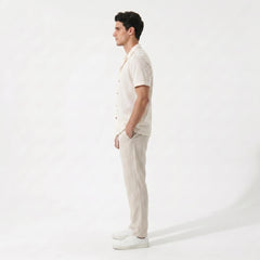 Side view of Man wearing beige geometric jacquard button up shirt and beige linen pants