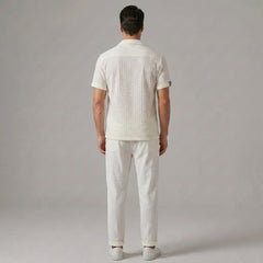 Back view of man wearing beige jacquard Cuban collar shirt and crinkle textured straight leg pants