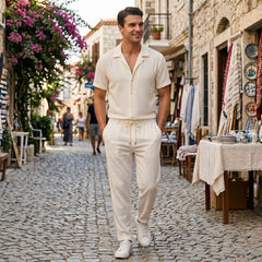 Man in beige jacquard Cuban collar shirt and crinkle pants walking in sunny summer outdoor scene