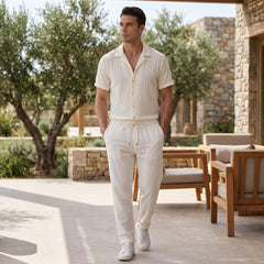 Man in beige jacquard Cuban shirt and crinkle pants in outdoor resort lifestyle setting