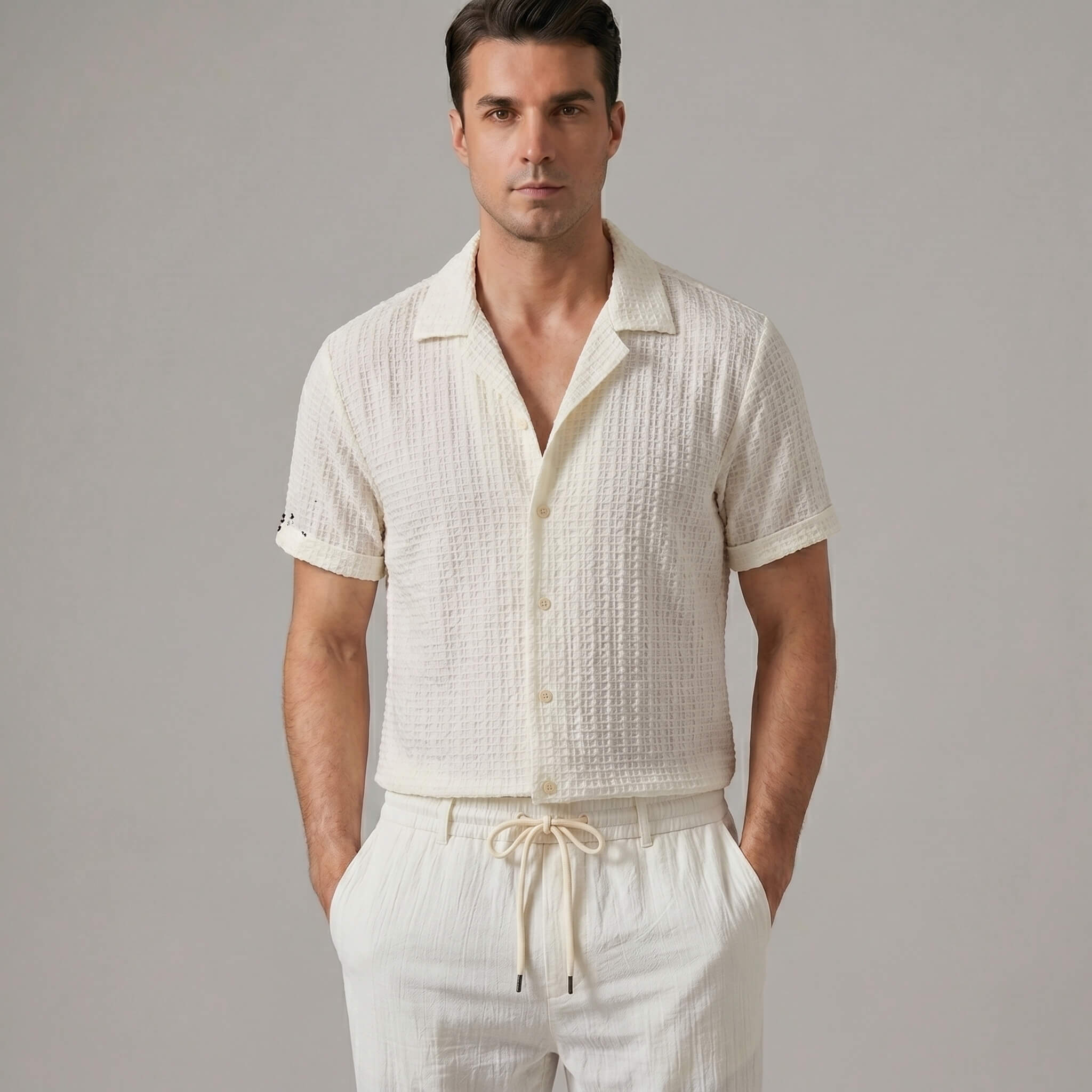 Three quarter view of man in beige jacquard Cuban shirt and crinkle pants on white background