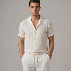 Three quarter view of man in beige jacquard Cuban shirt and crinkle pants on white background