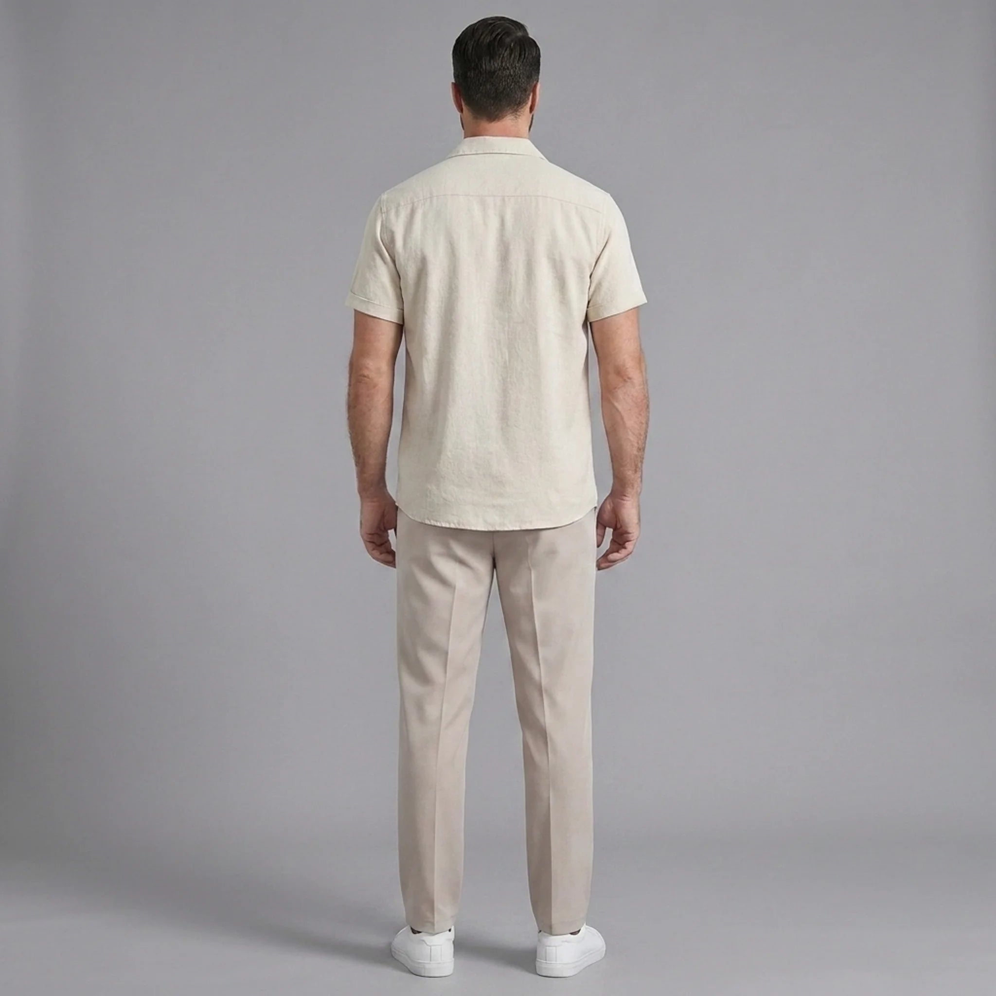 Back view of man wearing beige linen Cuban collar shirt and slim fit tapered trousers