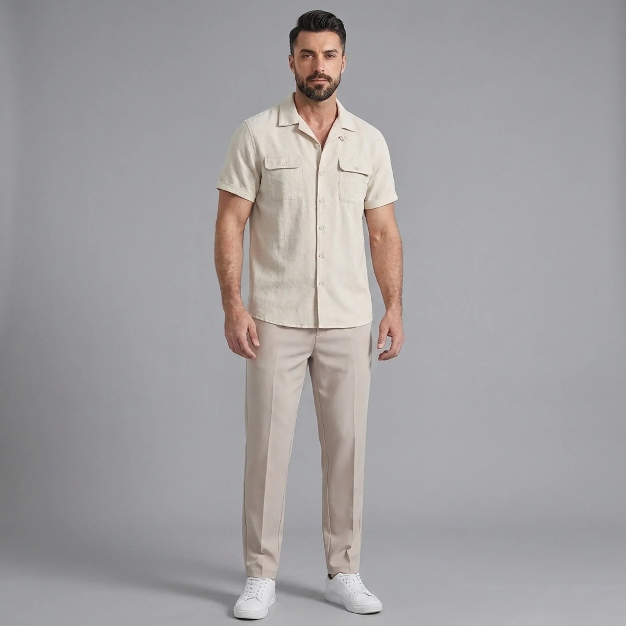Man wearing a beige linen Cuban collar shirt and slim fit tapered trousers front view on plain background