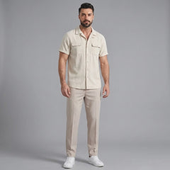 Man wearing a beige linen Cuban collar shirt and slim fit tapered trousers front view on plain background