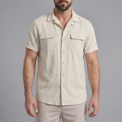 Three quarter view of man in beige linen Cuban collar shirt and slim fit tapered trousers